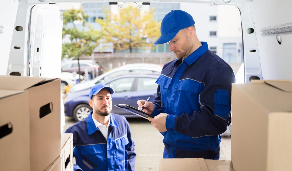 Mover Looking At His Partner Writing On Clipboard